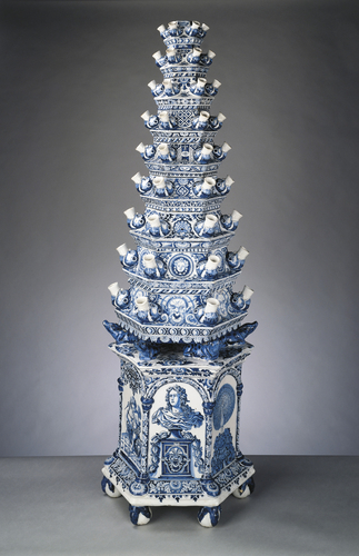 Tulip vase, Adriaen Kocks, 1694. Royal Collection Trust, UK.   Many of Queen Mary II's Delft vases were described in the inventories of her palaces at Het Loo and Hampton Court as standing on the hearth. Flower vases such as these were used to ornament the fireplace during the spring and summer when fires were not lit. Each of the nine hexagonal stages was made separately, with a sealed water reservoir and six protruding grotesque animal mouths, into which the cut stems of tulips or other flowers could be placed.