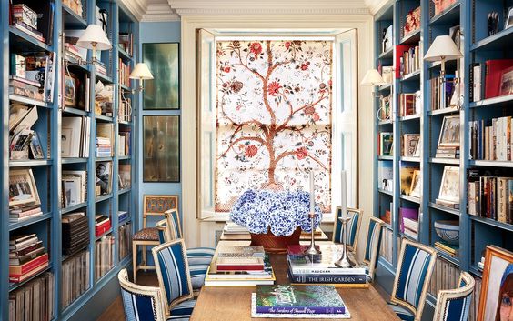 Caroline Sieber's dining-room library is crowded with the monographs that Caroline drew on for inspiration to design her London home —Jacques Grange, Elsie de Wolfe, and Madeleine Castaing among them. A panel of Braquenie's Tree of Life hangs on the window. Vogue UK. Oberto Gili photography